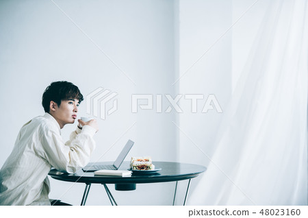 A man sitting in a chair and heading to a laptop 48023160
