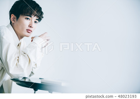 一個男人坐在椅子上，前往一台筆記本電腦 48023193