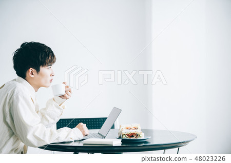 A man sitting in a chair and heading to a laptop 48023226
