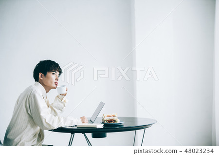 A man sitting in a chair and heading to a laptop A man sitting in a chair and heading to a laptop 48023234