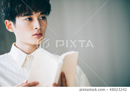 有一件白色襯衣的一個人在窗口旁邊讀書 有一件白色襯衣的一個人在窗口旁邊讀書 48023242