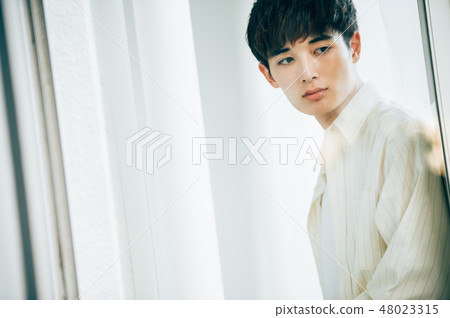 A man looking out the window through the glass 48023315