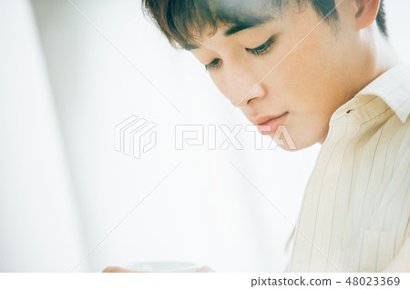 A man wearing a white shirt that looks through the glass 48023369