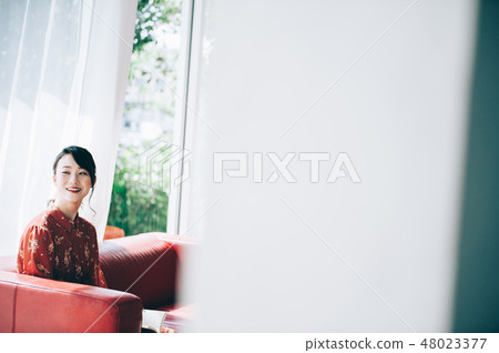 Sitting on a sofa on the window, reading a book A red one-piece lady who ups her hair 48023377