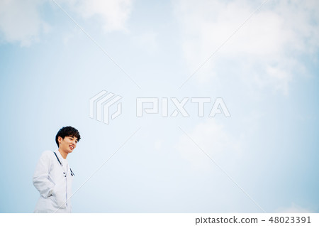 A man wearing a white robe standing on the roof 48023391