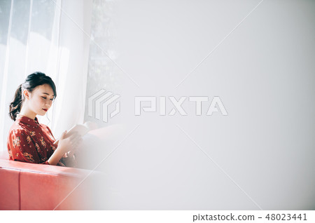 Sitting on a sofa on the window, reading a book A red one-piece lady who ups her hair 48023441