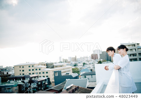 Men and women wearing white robes lined up on the roof 48023449