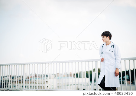 A man wearing a white suit on a railing on the roof 48023450