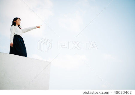 站立在屋頂的一件白色襯衣的一名婦女 站立在屋頂的一件白色襯衣的一名婦女 48023462