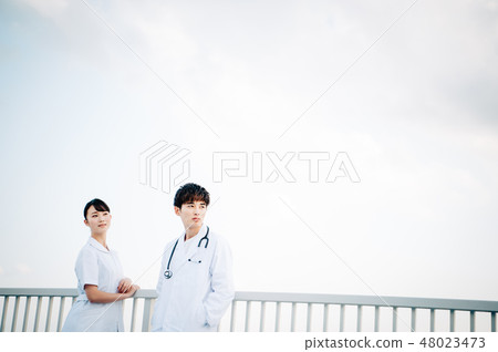 穿在欄杆的男人和婦女白色外套在屋頂 48023473