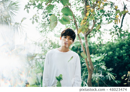 穿著一件白色T卹杉的一個人站立在庭院裡 穿著一件白色T卹杉的一個人站立在庭院裡 48023474