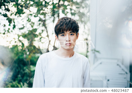 A man wearing a white T-shirt standing in the garden A man wearing a white T-shirt standing in the garden 48023487