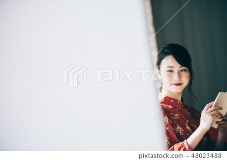 Sitting on a sofa on the window, reading a book A red one-piece lady who ups her hair Sitting on a sofa on the window, reading a book A red one-piece lady who ups her hair 48023488