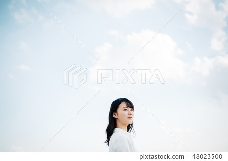 站立在屋頂的一件白色襯衣的一名婦女 48023500