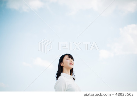 站立在屋頂的一件白色襯衣的一名婦女 48023502