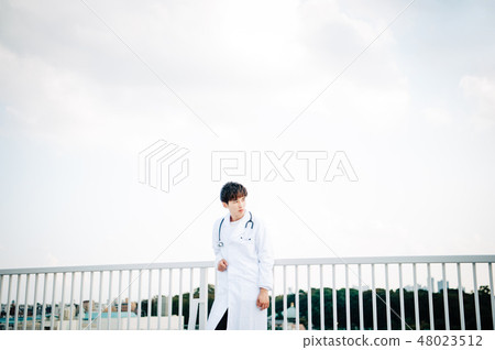 A man wearing a white suit on a roof railing 48023512