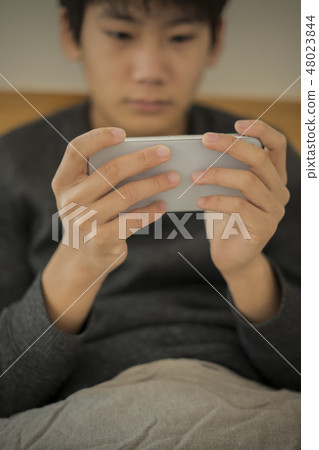 Boy using smartphone in bed Lack of sleep Junior high school student High school student body part Parts cut No face Boy using smartphone in bed Lack of sleep Junior high school student High school student body part Parts cut No face 48023844