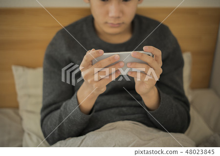 Boy using smartphone in bed Lack of sleep Junior high school student High school student body part Parts cut No face Boy using smartphone in bed Lack of sleep Junior high school student High school student body part Parts cut No face 48023845