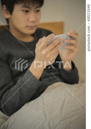 A boy who uses smartphone in bed sleep sleepy junior high school student high school student 48023846