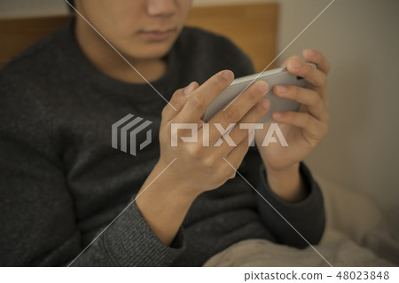 Boy using smartphone in bed Lack of sleep Junior high school student High school student body part Parts cut No face Boy using smartphone in bed Lack of sleep Junior high school student High school student body part Parts cut No face 48023848