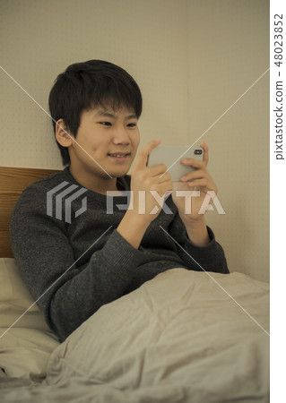 A boy who uses smartphone in bed sleep sleepy junior high school student high school student 48023852