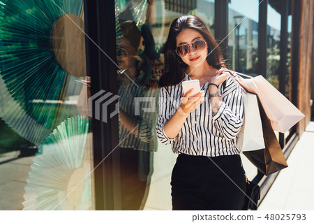 woman shopping bags rely against display window 48025793