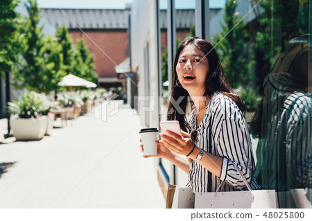 woman standing by fashion store window display 48025800