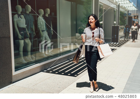 girl walking on a city street after shopping 48025803