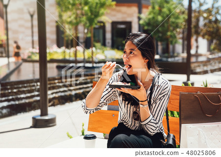asian lady having lunch outdoor on bench chair 48025806