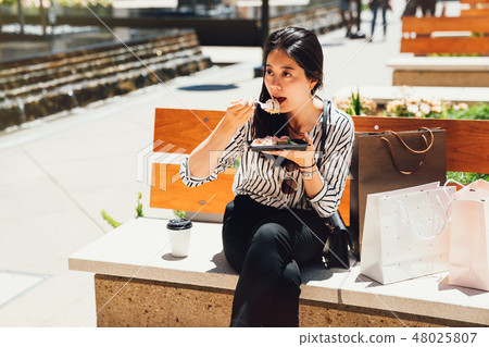 young chinese woman eating dessert outdoors young chinese woman eating dessert outdoors 48025807
