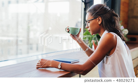 Young woman wearing eyeglasses with cup of coffee Young woman wearing eyeglasses with cup of coffee 48029271