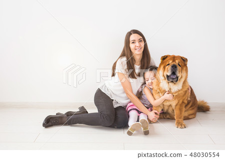 Pet, children and family concept - Little girl and her mother hugging chow-chow dog over white 48030554