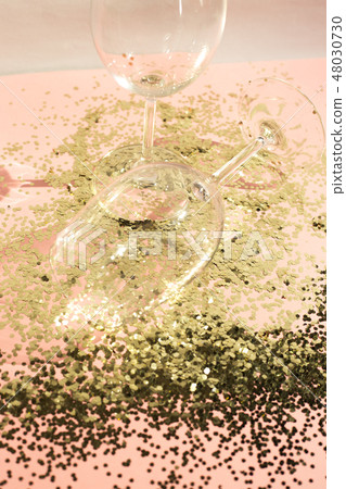 Empty glass goblets for champagne in golden confetti on the table. Festive background. Party concept Empty glass goblets for champagne in golden confetti on the table. Festive background. Party concept 48030730