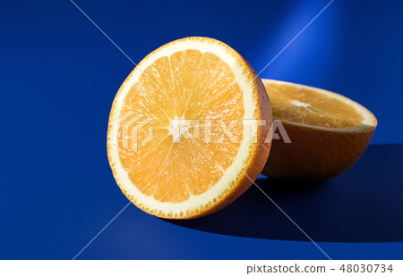 Two halves of ripe orange on a blue background in bright sunlight 48030734