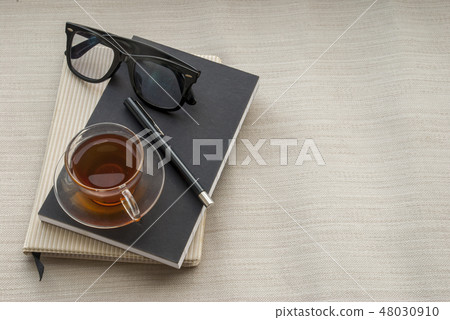 One glass pen, notebook, glasses and tea One glass pen, notebook, glasses and tea 48030910