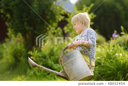 Cute toddler boy watering plants in the garden Cute toddler boy watering plants in the garden 48032454