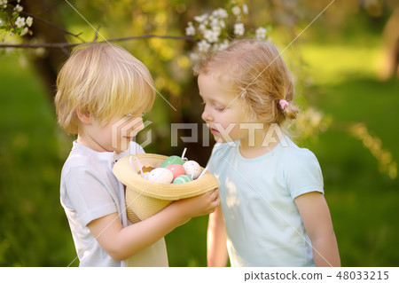 Charming little children hunts for painted eggs Charming little children hunts for painted eggs 48033215