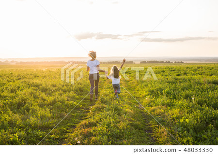 Family, summer and holiday concept - little daughter and mother run in the summer field Family, summer and holiday concept - little daughter and mother run in the summer field 48033330