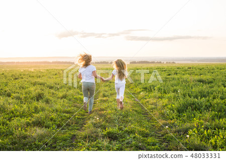 Family, summer and holiday concept - Back view of mother holding her daughter's hand running towards Family, summer and holiday concept - Back view of mother holding her daughter's hand running towards 48033331