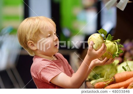 Cute little boy choosing fresh organic celery root Cute little boy choosing fresh organic celery root 48033846