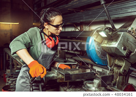 Busy and serious craftswoman grinding timbers with special machine. 48034161