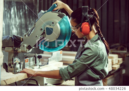 Busy and serious craftswoman grinding timbers with special machine. Busy and serious craftswoman grinding timbers with special machine. 48034226