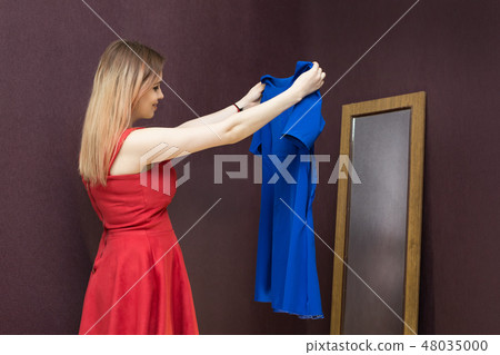 The girl in the fitting room chooses a dress. 48035000
