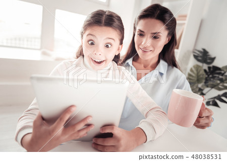 Emotional little schoolgirl feeling astonished after seeing unexpected message Emotional little schoolgirl feeling astonished after seeing unexpected message 48038531