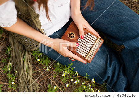 Woman holding kalimba in her hands and playing 48049116
