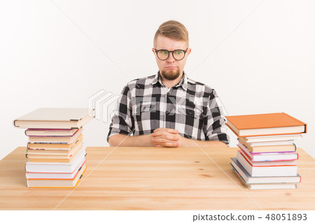 People, knowledge and education concept - Tired male student sitting at the table with mountains of People, knowledge and education concept - Tired male student sitting at the table with mountains of 48051893