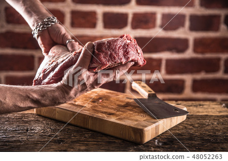 Butcher man hands holding raw beef steak. Butcher man hands holding raw beef steak. 48052263