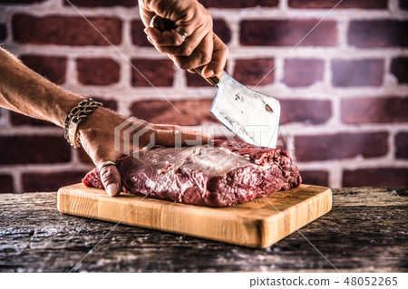 Butcher man hands cutting raw beef steak. Butcher man hands cutting raw beef steak. 48052265