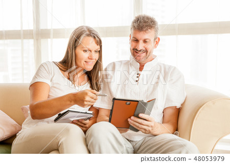 Mature couple on a couch with tablet Mature couple on a couch with tablet 48053979