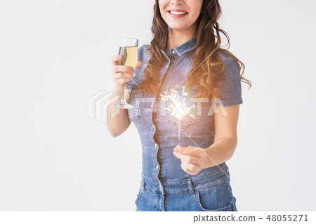 Celebration, drinks and holiday concept - close up of young woman with sparkler and glass of Celebration, drinks and holiday concept - close up of young woman with sparkler and glass of 48055271